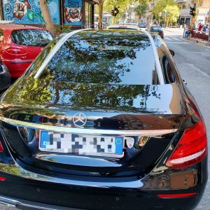 Addobbi auto matrimonio con nastri bianchi tesi sul tetto di una berlina nera parcheggiata in citta.